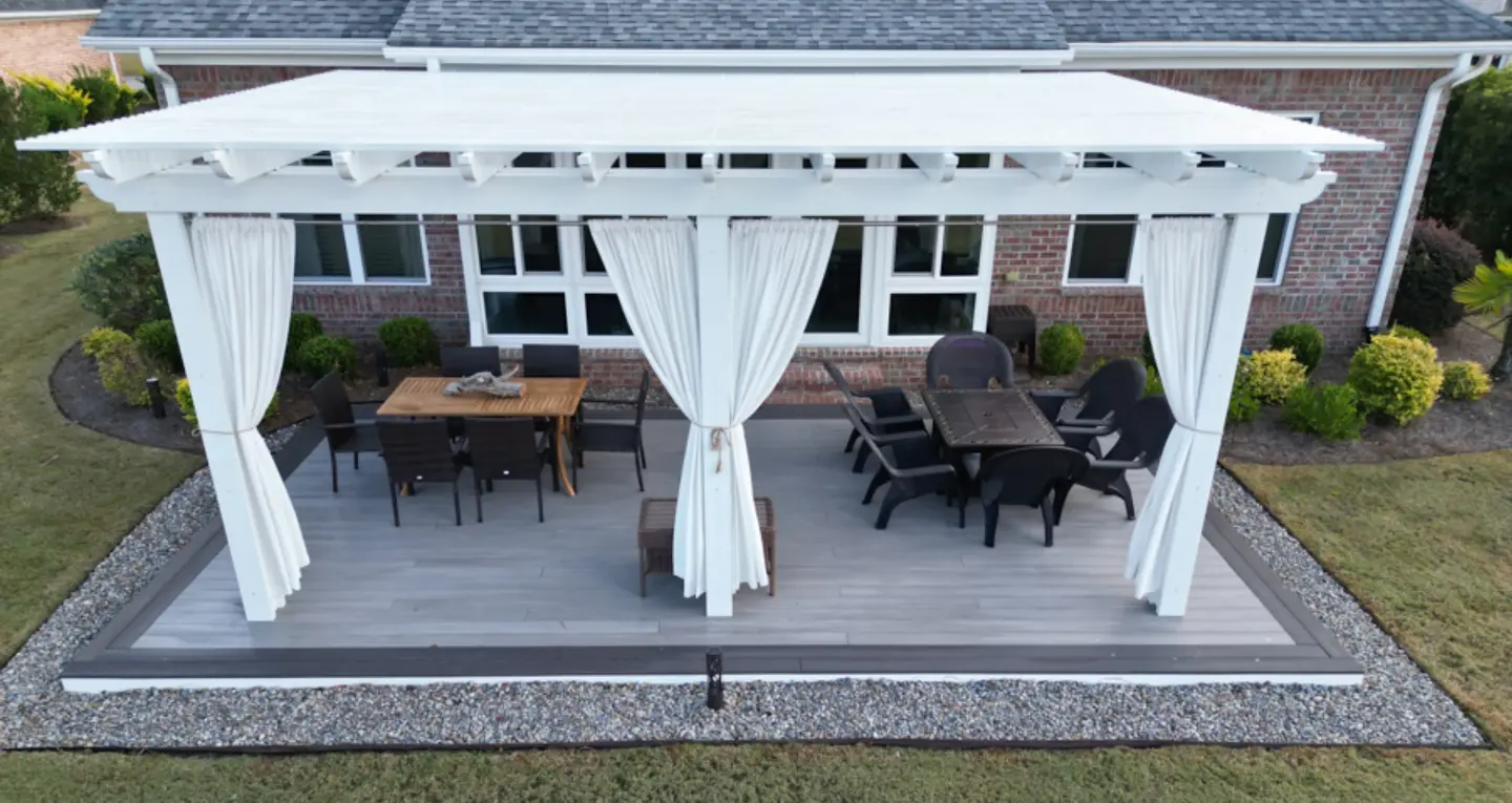 Backyard pergola with white curtains and patio furniture